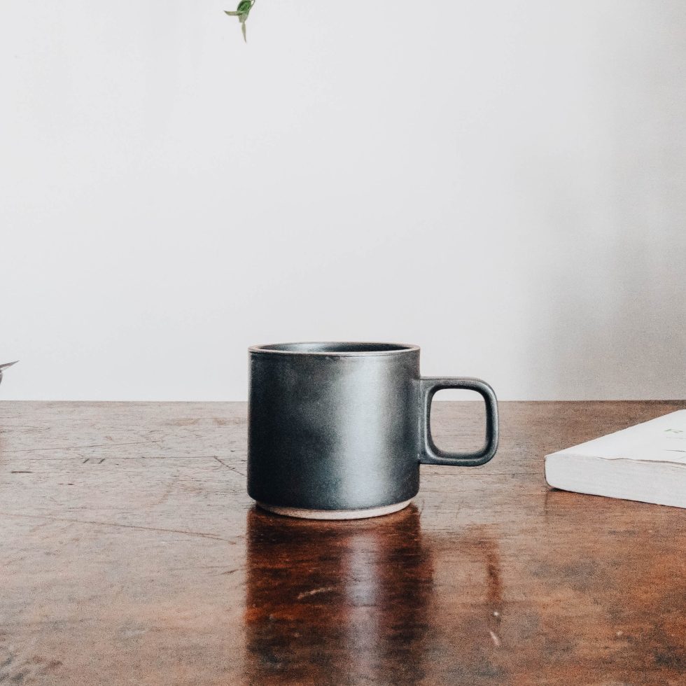 Taza de café negra en una mesa de madera.